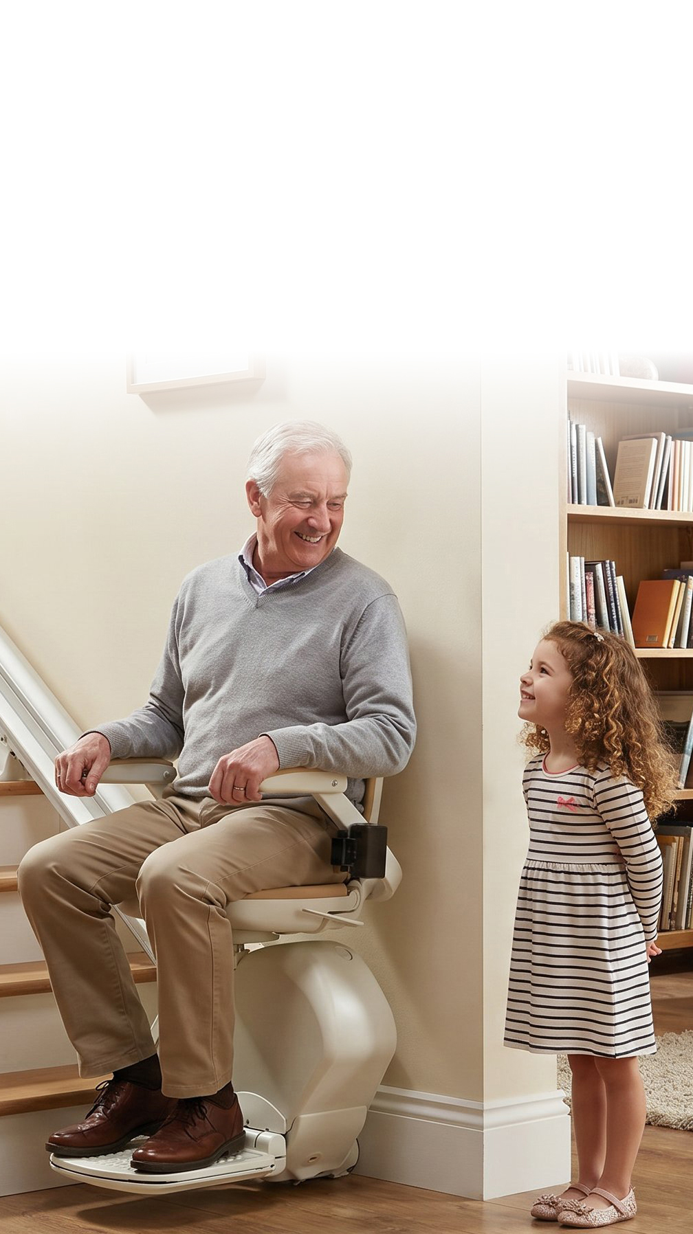 Older man using a stairlift safely at home with his granddaughter nearby