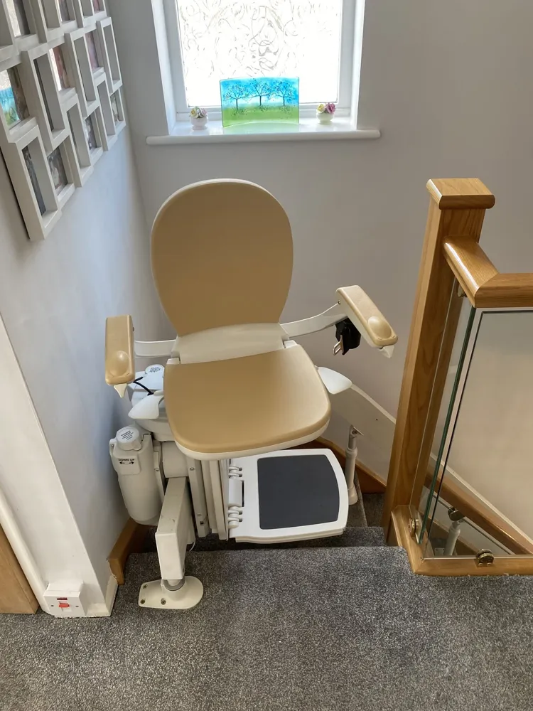 Curved stairlift parked at the top landing, showing the made-to-measure rail end