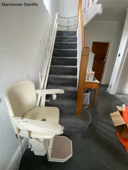 Curved stairlift fitted at the bottom of a turning staircase in a Greater Manchester home